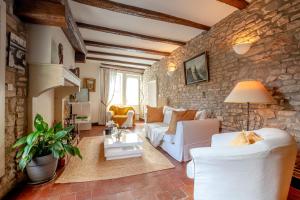 a living room with white furniture and a stone wall at La "Petite" Maison in Saint-Romain
