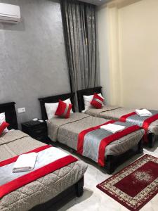 Habitación de hotel con 3 camas con almohadas rojas en Hotel Biarritz en Tánger