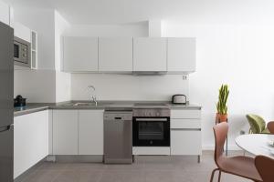 a kitchen with white cabinets and a sink and a stove at Royal Flats in Las Palmas de Gran Canaria