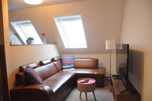 a living room with a brown leather couch and two windows at Ursprung Apartments in Rostock