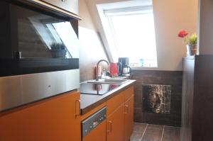 a kitchen with orange cabinets and a sink and a window at Ursprung Apartments in Rostock