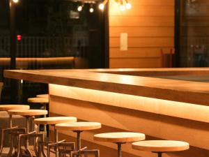 - une rangée de tabourets au bar d'un restaurant dans l'établissement UMEDAHOLIC HOTEL, à Osaka