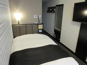 um pequeno quarto com uma cama e uma televisão de ecrã plano em APA Hotel Utsunomiya-Ekimae em Utsunomiya