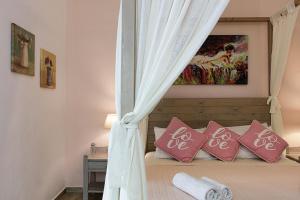 1 dormitorio con cama con dosel y almohadas rosas en Kasteli Studios & Apartments, en Panormos Rethymno