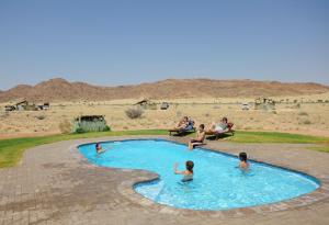 a group of people in a swimming pool in the desert at Sossus Oasis Campsite in Sesriem