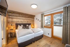 1 dormitorio con 1 cama y pared de madera en sWiederkehr, en Schladming