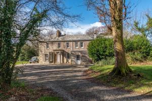 una vecchia casa in pietra con alberi di fronte di The Manor House at Boconnion a Bodmin