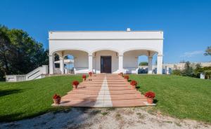 un edificio bianco con una scala nell'erba di Villa Flem Luxury by HDSalento a Montesano Salentino