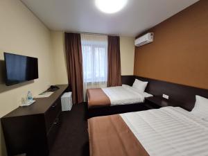 um quarto de hotel com duas camas e uma televisão de ecrã plano em EVEREST ОТЕЛЬ em Poltava