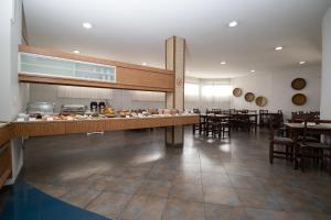 a restaurant with a counter and tables and chairs at Hotel Bramig in Itajubá