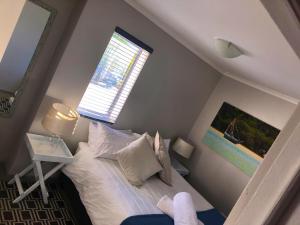 um pequeno quarto com uma cama e uma janela em Red Bench Cottage em St Helena Bay