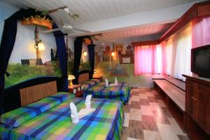 a hotel room with three beds and a tv at Kokosnuss Garden Resort in Coron
