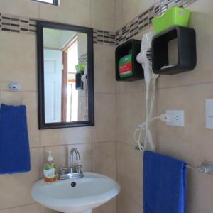 baño con lavabo, espejo y TV en Villa Segura Manuel Antonio, Quepos, en Quepos