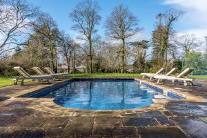 una piscina con 2 sedie a sdraio e una piscina di The Manor House at Boconnion a Bodmin