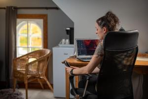 a woman sitting in a chair in front of a desk with a laptop at Manoir D'Orsennens in Lac-Mégantic