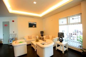 a living room with white furniture and a large window at Merdeka Suites Hotel in Miri