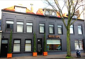 Un edificio negro con una motocicleta estacionada enfrente. en Boutique Hotel Lupo, en Vlissingen
