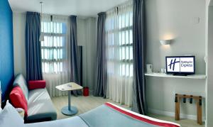 Habitación con cama, sofá y ventanas. en Holiday Inn Express Ciudad de las Ciencias, an IHG Hotel en Valencia
