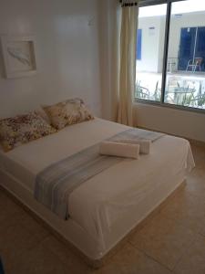 1 cama blanca grande en una habitación con ventana en Hotel Portobello, en Coveñas