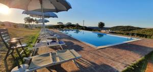 a swimming pool with chairs and umbrellas next to a pool at Hotel Tenuta dell'Argento Resort in Civitavecchia