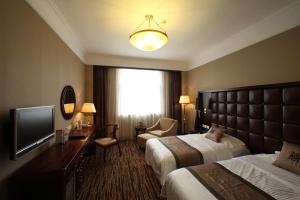 a hotel room with two beds and a flat screen tv at Jianguo Qianmen Beijing in Beijing