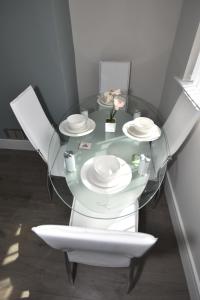 a glass table with two white chairs and plates on it at Townhouse @ Penkhull New Road Stoke in Stoke on Trent