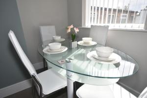 a glass table with cups and saucers and two chairs at Townhouse @ Penkhull New Road Stoke in Stoke on Trent