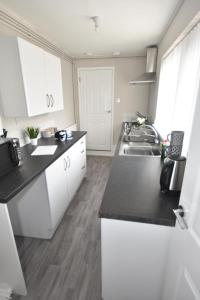 a kitchen with white cabinets and a sink at Townhouse @ Penkhull New Road Stoke in Stoke on Trent