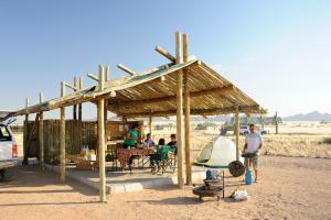 a group of people standing under a wooden pavilion at Sossus Oasis Campsite in Sesriem
