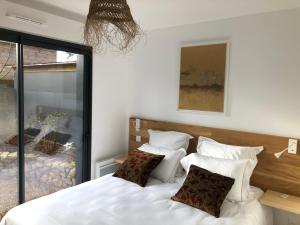una camera da letto con letto, lenzuola e cuscini bianchi di Cottages du Valcoquet a Saint-Brévin-les-Pins