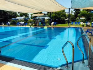 a large swimming pool with blue chairs and an umbrella at Erettz Dafna Travel Hotel in Metsudat Menahem Ussishkin Alef