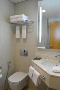 a bathroom with a sink and a toilet and a mirror at Ibis Abu Dhabi Gate in Abu Dhabi