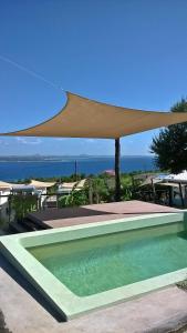 a swimming pool with a large umbrella over it at Shaquila Lodge in Fernão Veloso