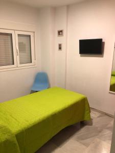 1 dormitorio con 1 cama verde y 1 silla azul en Casa de los Tilos en Mairena del Aljarafe