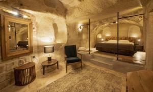a bedroom with a bed and a chair and a mirror at Luvi Cave Hotel in Göreme +78 photos