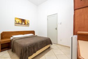 a small bedroom with a bed and a door at OYO Residencial Itacuruçá Apart Hotel in Itacuruçá