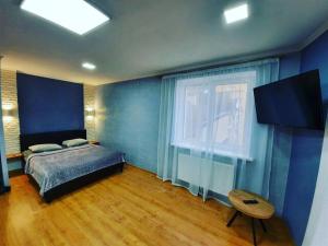 a bedroom with blue walls and a bed and a table at Podobovo-ivano-frankivsk.com in Ivano-Frankivsʼk