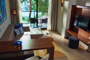 un soggiorno con un divano, una TV e un tavolo di TUI BLUE Seno - Adults Only a Sarigerme