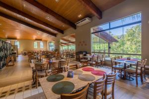 ein Esszimmer mit Tischen und Stühlen und einem großen Fenster in der Unterkunft Rio Quente Resorts - Hotel Luupi in Rio Quente