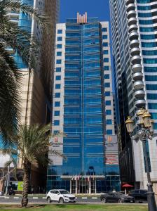 un grand bâtiment bleu avec des voitures garées devant lui dans l'établissement Copthorne Hotel Sharjah, à Charjah