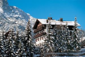 un bâtiment recouvert de neige à côté d'une montagne dans l'établissement Wellness Hotel Bladen, à Sappada