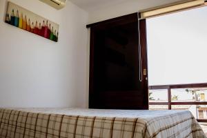 um quarto com uma cama e uma porta com uma janela em Tamandare Residence em Tamandaré