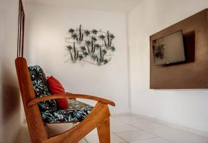 Habitación con silla y TV en la pared. en Tamandare Residence, en Tamandaré