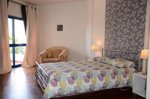 a bedroom with a bed and a chair and a window at The Sea at Your Fingertips in Cascais