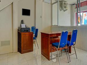 uma sala com cadeiras azuis e uma mesa com um micro-ondas em RedDoorz at Jalan Somba Opu Losari em Macáçar