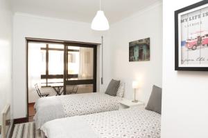 two beds in a white room with a window at Cascais Guia’s Gorgeous & Spacious Apartment in Cascais