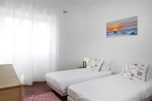 two beds in a room with white walls at Comfortable and Central Apartment Cascais in Cascais