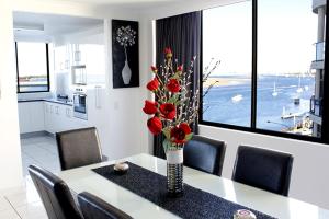 a dining room table with a vase of red flowers on it at Beaconlea in Gold Coast