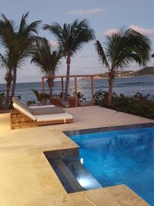 - une piscine bordée de palmiers à côté de l'océan dans l'établissement VILLA OYONO THE CARRIBEAN DREAM, à Saint Barthelemy