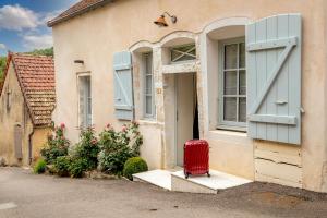 una valigia rossa seduta fuori da una casa di Les Demeures du Tonnelier, Maison Rue a Saint-Romain Altre 4 foto